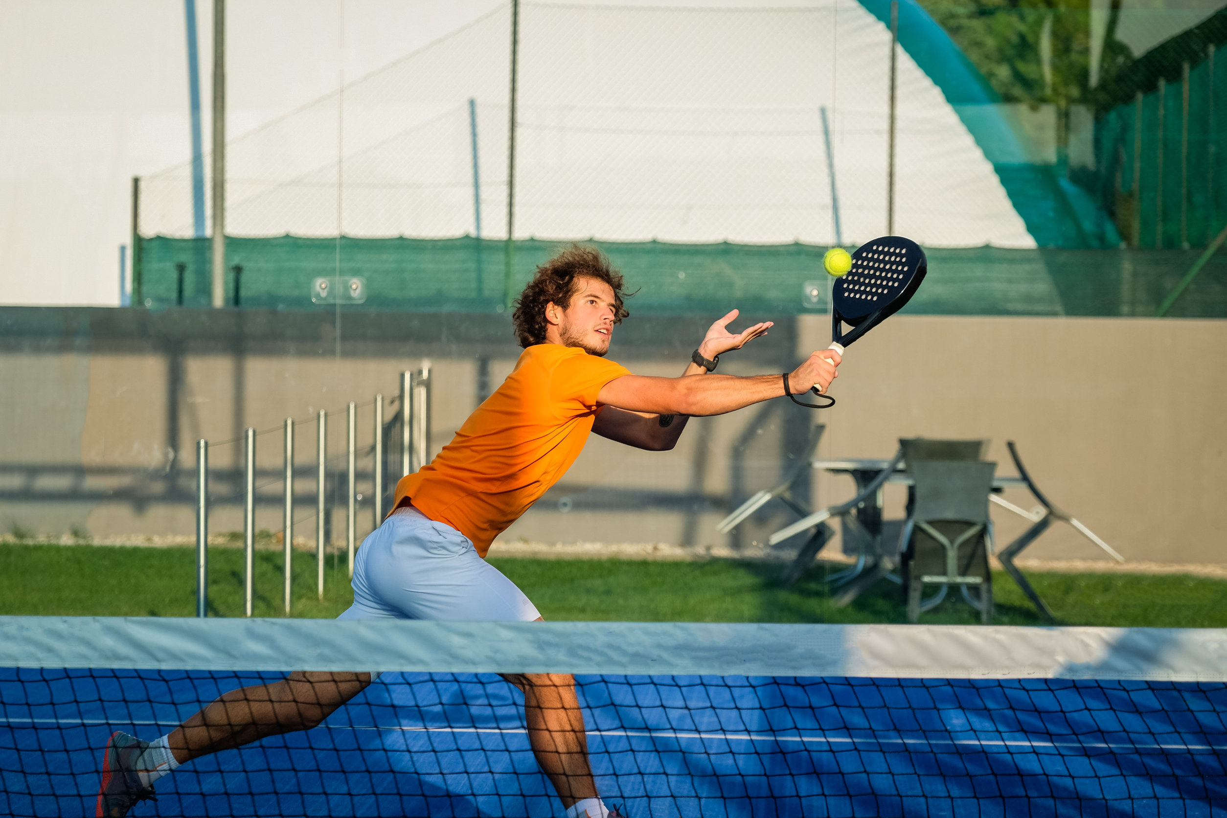 Padel match in a blue grass padel court - Padel player playing a